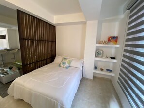 Relax in a serene space with a neatly made bed, wooden headboard, and stylish shelving.