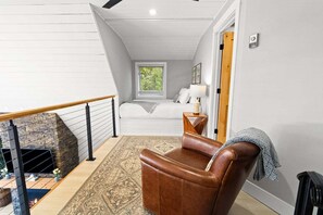 Un intérieur moderne avec une cheminée en pierre, un canapé en cuir, un lit avec vue et un escalier.