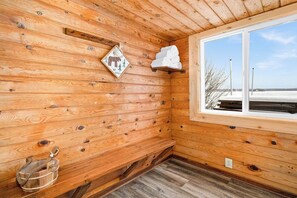 Ein Interieur einer Holzhütte mit Fenster, Wandheizung und einer hölzernen Bank.