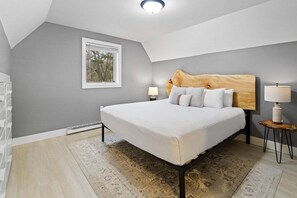 Une chambre à coucher avec un lit, des tables de chevet, une fenêtre et un luminaire au plafond.