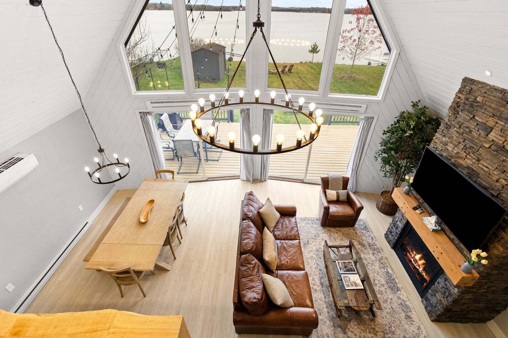 A spacious living room with a large window, a fireplace, a sofa, and a dining area.