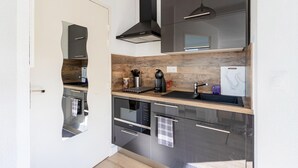 Una cocina moderna con electrodomésticos de acero inoxidable, un protector contra salpicaduras de madera y una campana extractora negra.