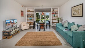 A modern living room with a sofa, TV, and a dining area with chairs and a table. - Casavento Puzziteddu 6 Emma Villas (Campobello di Mazara)
