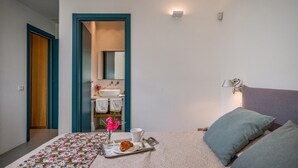 A bedroom with a bed, a bedside table with a cup, a tray with a croissant, and a vase with flowers. - Casavento Puzziteddu 6 Emma Villas (Campobello di Mazara)
