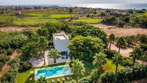 An aerial view of a modern villa with a swimming pool, surrounded by lush greenery and a view of the sea. - Casavento Puzziteddu 6 Emma Villas (Campobello di Mazara)