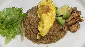 A plate with brown rice, grilled chicken, a fried egg, avocado slices, and lettuce.