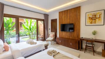 Habitación de hotel con dos camas, un escritorio, un televisor y un ventanal con vistas a zonas verdes.