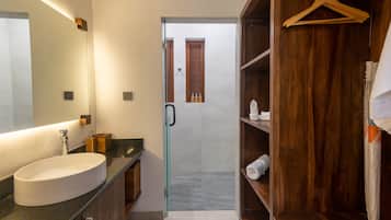 Um banheiro moderno com uma pia oval grande, box de vidro e prateleiras de madeira.