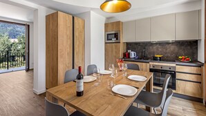 A modern kitchen with wooden cabinets, a built-in microwave, and a dining area with a wooden table set for four. - Porto Letizia Rossini 9, Porlezza, Italy (Porlezza)