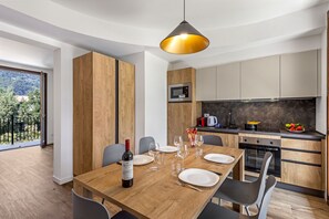 A modern kitchen with wooden cabinets, a built-in microwave, and a dining area with a wooden table set for four.