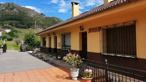 A yellow building with a tiled roof and a balcony with potted plants. - La Rectoral Arriondas (Arriondas)