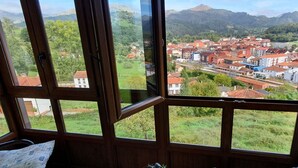 A room with large windows offering a view of a town and mountains. - La Rectoral Arriondas (Arriondas)