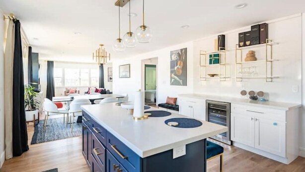 A modern kitchen with a central island, white cabinetry, and pendant lighting.