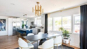 A modern kitchen with white cabinets, a central island, and a dining area with a dark table and white chairs.