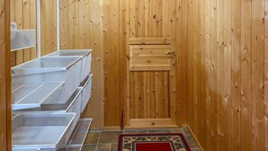 A wooden-paneled room with a door, metal storage units, and a patterned rug.