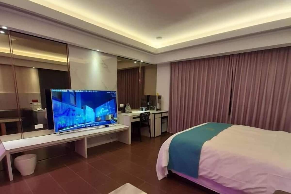 Une chambre d’hôtel avec un grand lit, un bureau, une télévision et une petite table.