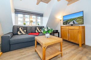 Uma sala de estar aconchegante com um sofá cinza, uma mesa de centro de vime e um armário de madeira.