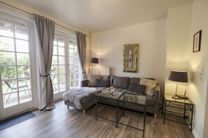 A living room with a sofa, a glass coffee table, and two lamps.