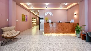Un espace d’accueil comprenant un comptoir de réception, une chaise d’attente et une plante en pot.