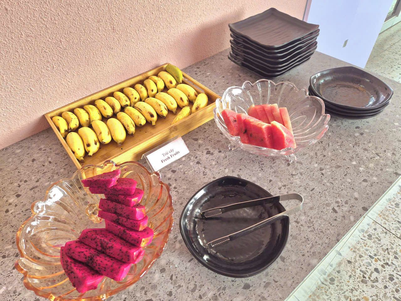 A buffet table with a variety of fruits and a stack of plates.