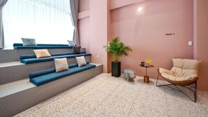 Un intérieur moderne avec un escalier, des sièges rembourrés bleus, une plante en pot, une chaise et un panneau indiquant la direction des toilettes.