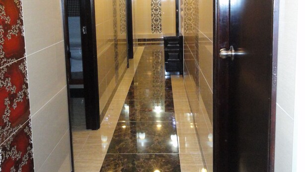 A hallway with a marble floor, patterned walls, and a door with a metallic handle. - Bohol Hostel (Kowloon)