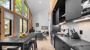 A modern kitchen with large windows, a dining area, and a staircase. - Black Diamond: "Waterfront Finger Lakes Home with Hot Tub!" (Hector)