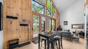 A modern interior with a wooden wall, large windows, a dining area, and a kitchen. - Black Diamond: "Waterfront Finger Lakes Home with Hot Tub!" (Hector)