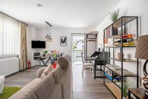 Ein modernes Wohnzimmer mit Sofa, Fernseher, Essbereich und Bücherregal.
