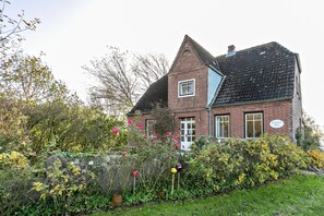 A brick house with a sloped roof, a small window, and a sign reading 'Swanen Haus.' - Hygge Frisian House by the Sea with Private Garden and Terrace (Nordstrand)