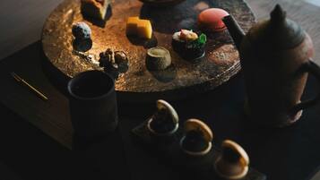 A round wooden table with various food items and a teapot.