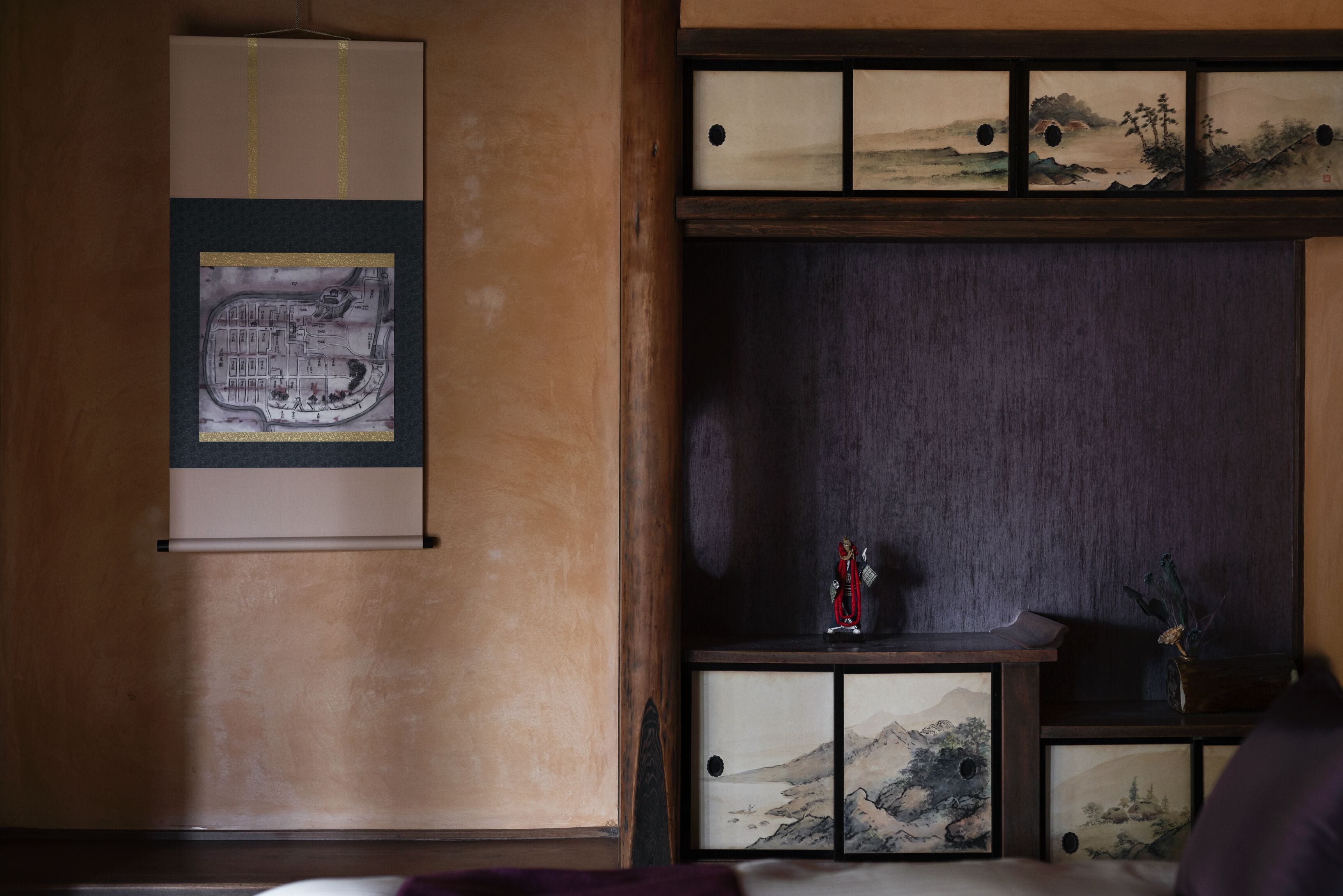 Una tradizionale stanza in stile giapponese con pavimento in tatami, paravento shoji e un mobiletto in legno basso con calligrafia e dipinti.