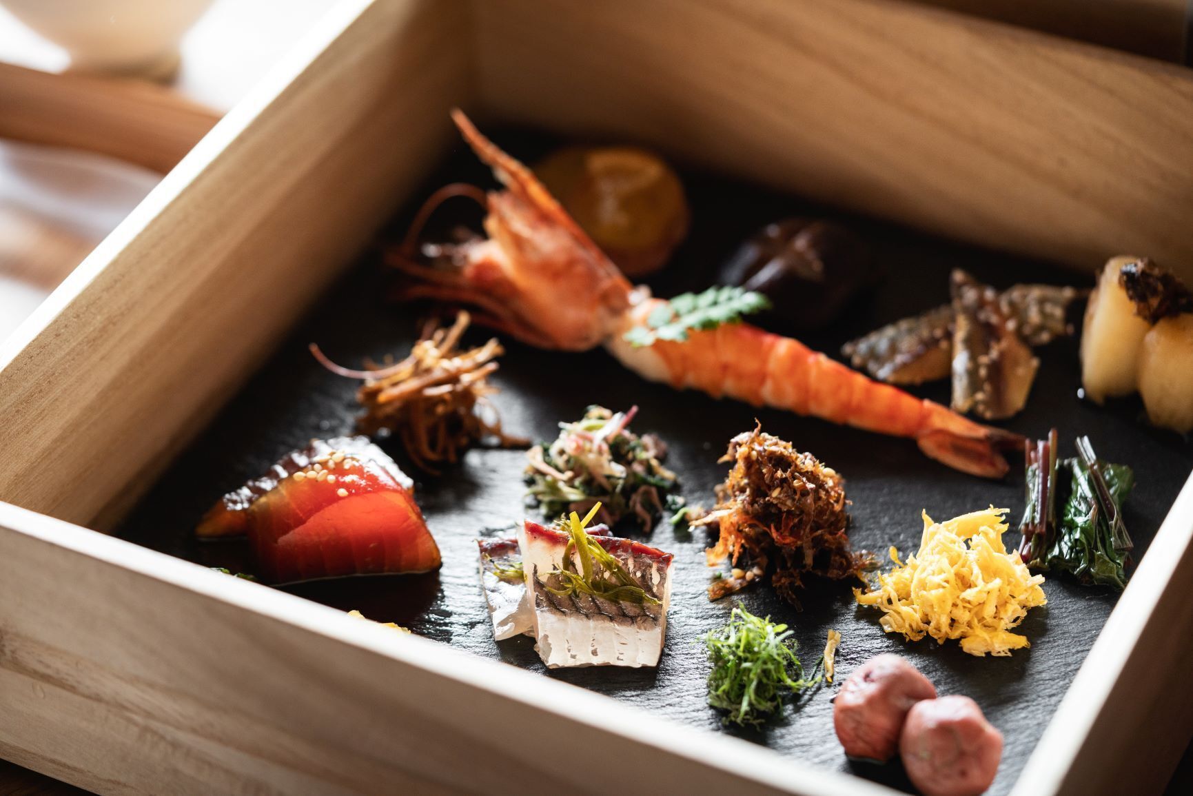 Une boîte en bois contenant divers plats de fruits de mer.