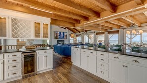 A spacious kitchen with white cabinets, a built-in dishwasher, and a large island.