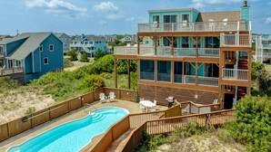 A two-story house with a swimming pool, wooden deck, and a view of neighboring houses.