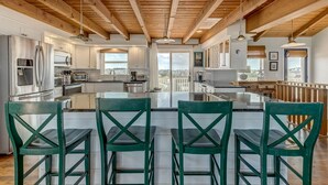 A modern kitchen with wooden beams, stainless steel appliances, and a central island with bar stools.