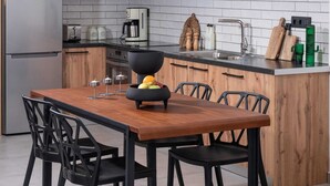 A modern kitchen with grey cabinets, a wooden dining table, and a hanging light fixture.