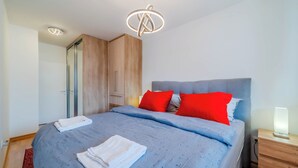 A modern bedroom with a large bed, wooden wardrobe, and a bedside table with a lamp. - Apartment Saga With Terrace And Parking (Zagreb)