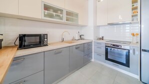 A modern kitchen with grey cabinets, a black microwave, a built-in oven, and a stainless steel refrigerator. - Apartment Saga With Terrace And Parking (Zagreb)