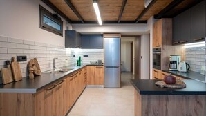 Cuina moderna amb armaris de fusta, nevera d'acer inoxidable i taulell negre.