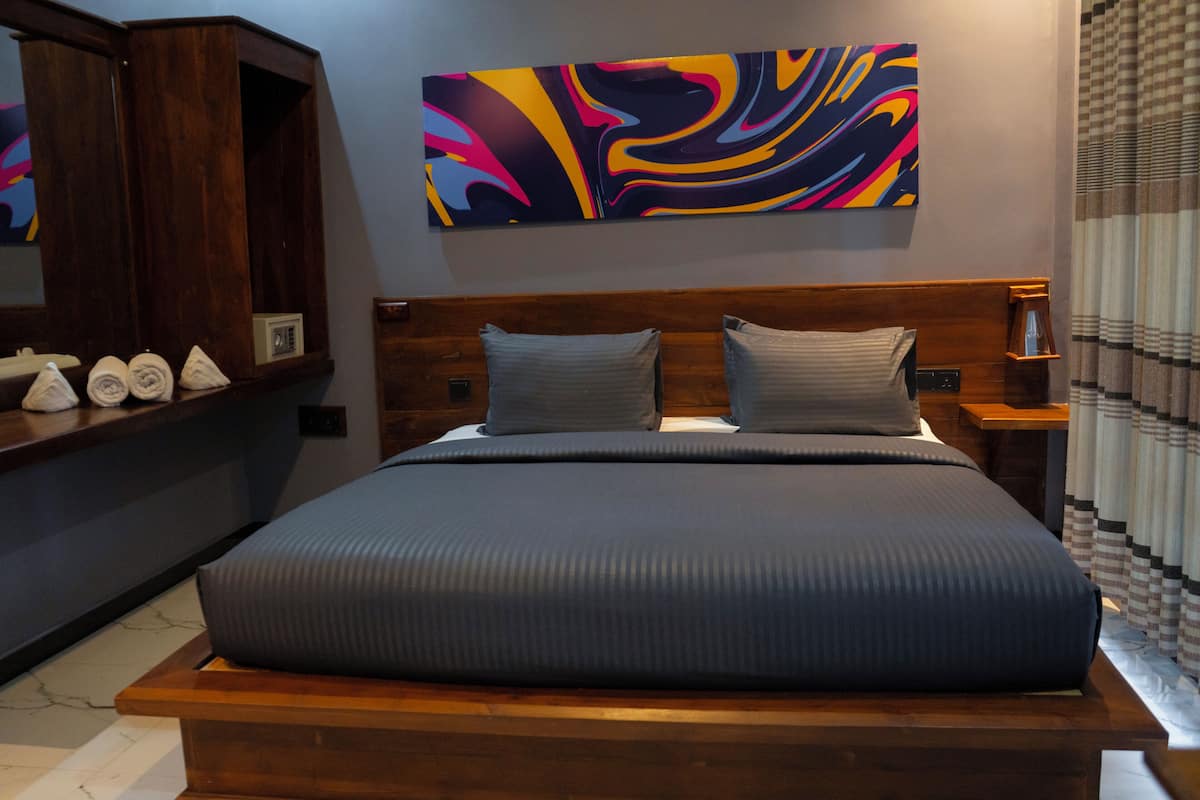 Quarto moderno com uma cama grande, cabeceira de madeira e um quadro abstrato colorido acima.