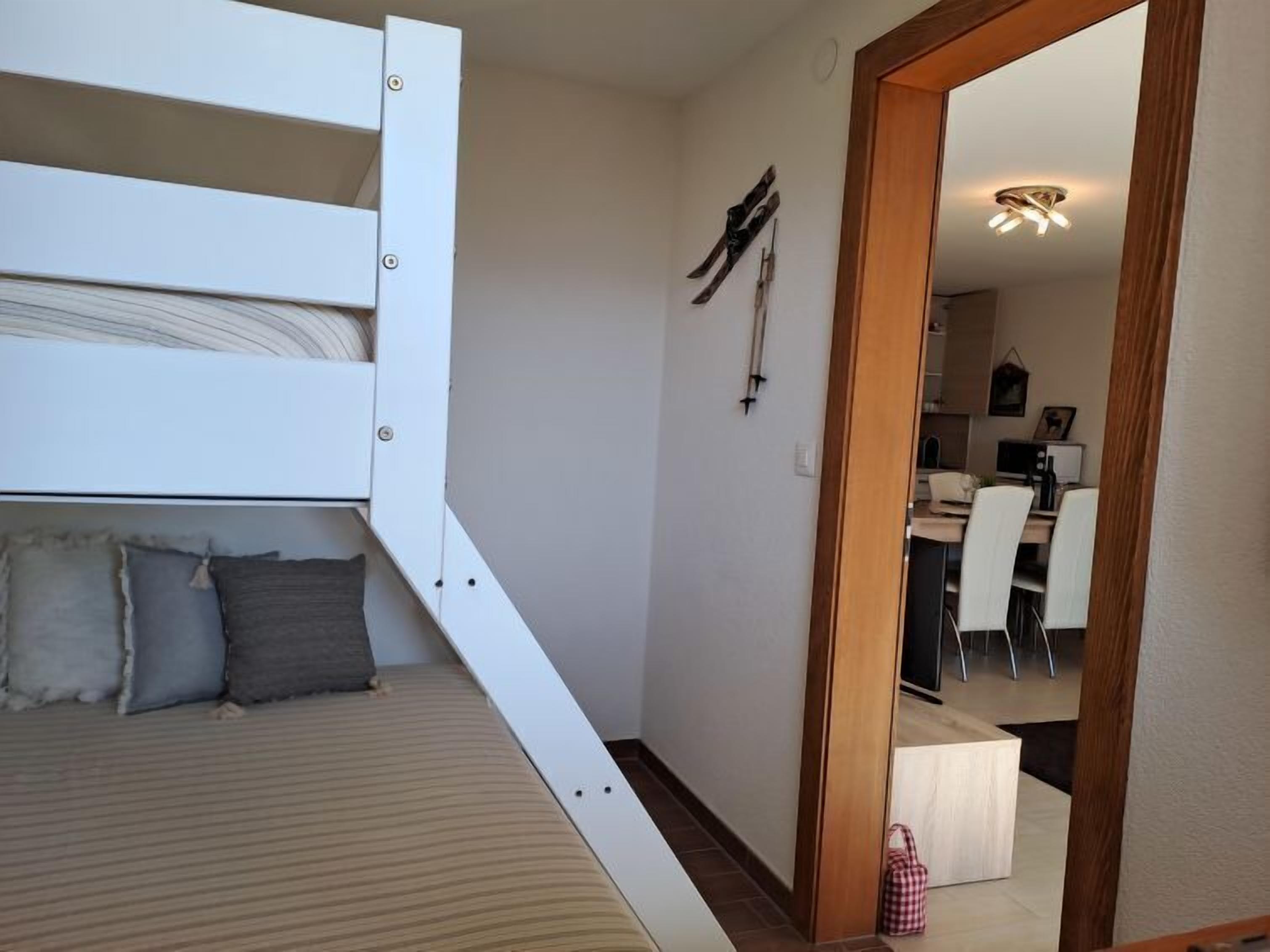 Een kleine kamer met een stapelbed, een bureau en een stoel.