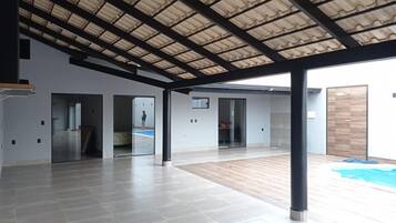 Uma sala de estar integrada com pé direito alto, piscina e deck de madeira.