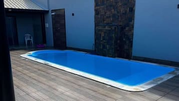 Piscina retangular com interior azul, rodeada por um deck de madeira.