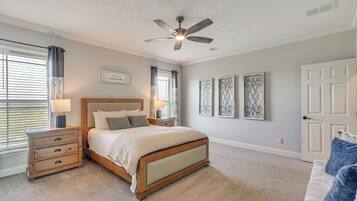 Ein Schlafzimmer mit Bett, Nachttischen, Deckenventilator und Wandbildern.