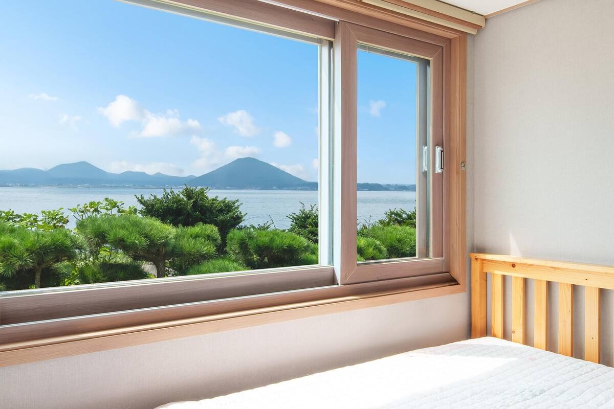 Une chambre dotée d’une grande fenêtre donnant sur un lac et des montagnes.