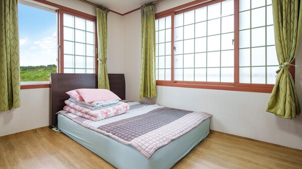 Un dormitorio con cama, cortinas verdes y vistas al exterior.