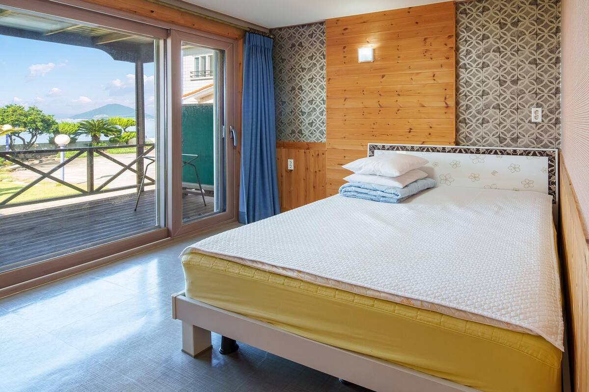 Une chambre avec un lit, une vue sur l’extérieur et un mur en bois.