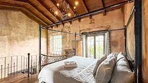 Un dormitorio con cama con dosel, un balcón y vistas a la vegetación.