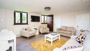Ein modernes Wohnzimmer mit einem weißen Couchtisch, beigen Sofas und einem gelben Teppich mit Muster.